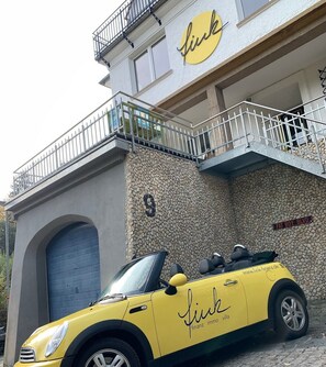 A yellow convertible car parked in front of a building with a stone facade, a balcony, and a sign reading 'FAT BOY BLVD.' - Holiday flat "Villa Fink Obergeschoss" with mountain view, private terrace and wifi. (Schramberg)
