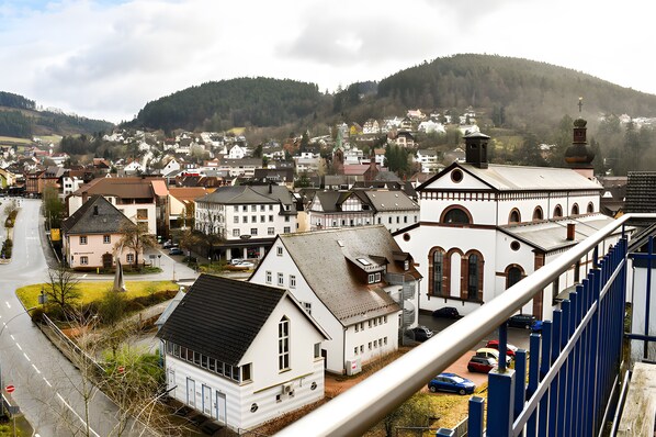 A town with a prominent church, a street with parked cars, and a hill in the background. - Holiday flat "Villa Fink Obergeschoss" with mountain view, private terrace and wifi. (Schramberg)