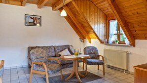 A cozy room with a wooden ceiling, a sofa, two chairs, a small table, and a picture on the wall. - Apartment Afterglow (Oberried-St. Wilhelm)
