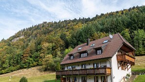 A two-story house with a balcony, a covered porch, and a hillside view. - Apartment Afterglow (Oberried-St. Wilhelm)