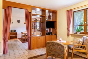 Un salon équipé d’un téléviseur, de meubles en bois, d’une table à manger et de chaises.