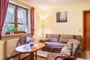 A cozy living room with a sofa, a table, a potted plant, and a lamp. - Apartment Wiesengrund (Oberried-St. Wilhelm)