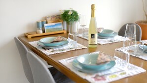 Een eettafel gedekt met borden, glazen en een fles wijn.