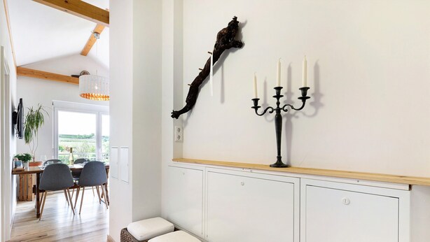 Een kamer met een eethoek, een kandelaar en een wandsculptuur.