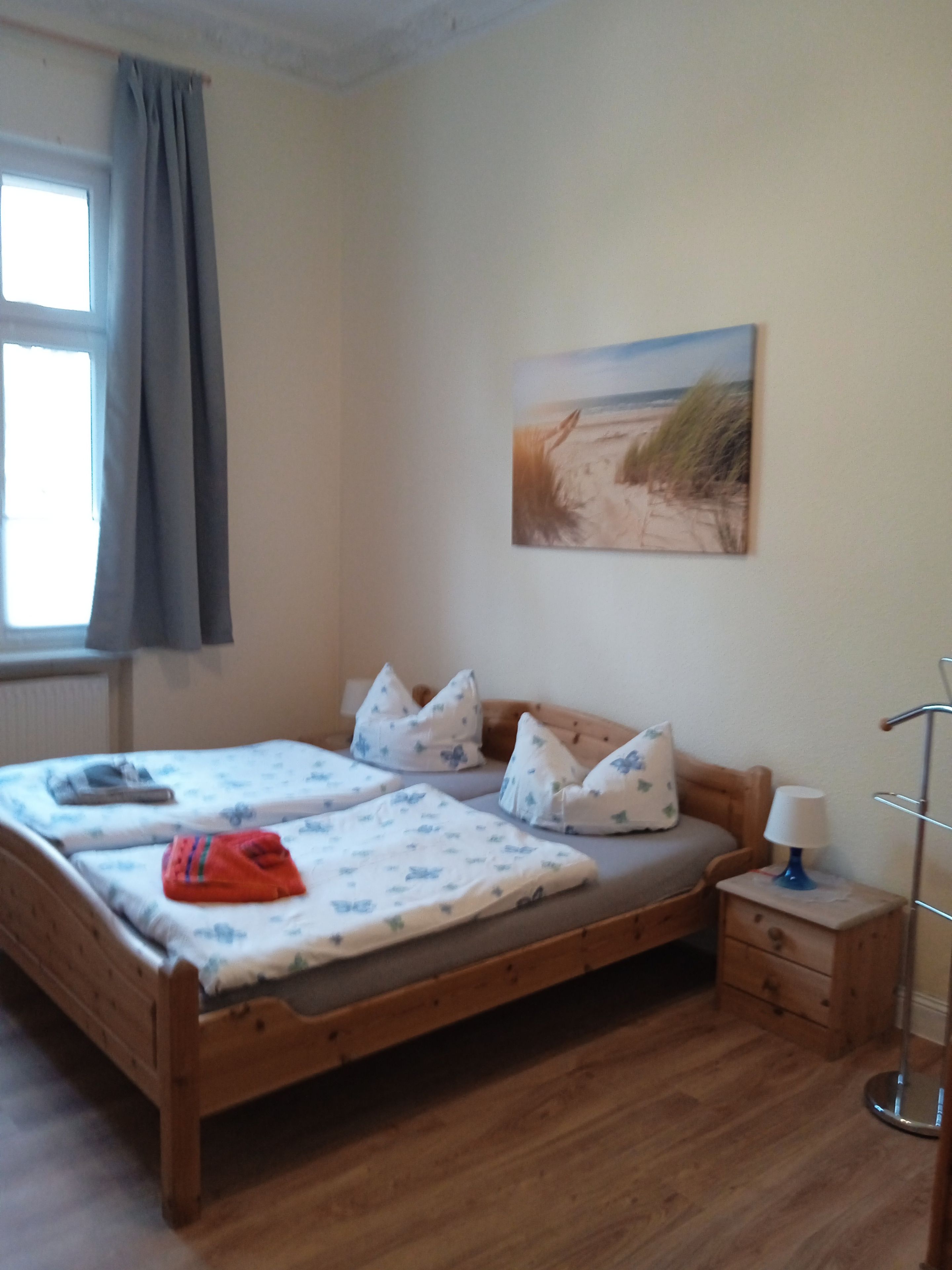 Un dormitorio con una cama de madera, una mesita de noche, una lámpara y un cuadro con una playa.