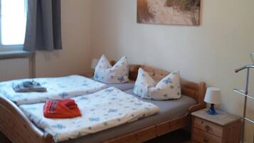 Un dormitorio con una cama de madera, una mesita de noche, una lámpara y un cuadro con una playa.