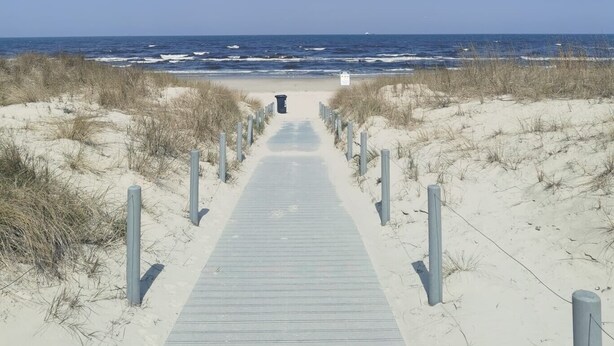 A wooden boardwalk leading to a beach with sand dunes and a clear blue sky. - Apartment "Villa Adler - Waldseite" (Seebad Ahlbeck)
