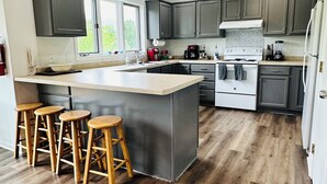 A modern kitchen with a large island, wooden stools, and a view of the outdoors. - Galena 4BR • 4 Private Baths • Sleeps 10 • Game Room • Owners’ Club (Galena)