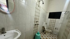 A bathroom with a sink, toilet, shower, and a mirror. - Shree Katyayani Residency (Gokarna)