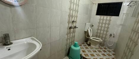 Et badeværelse med vask, toilet, bruser og spejl.