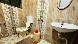 A small bathroom with a toilet, a sink, and a shower. - Shree Katyayani Residency (Gokarna)