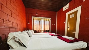 A hotel room with two beds, red brick walls, a wooden door, and a window with curtains. - Shree Katyayani Residency (Gokarna)