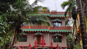 A multi-story building with a traditional architectural style, featuring a balcony with red railings and a decorative gate at the entrance. - Shree Katyayani Residency (Gokarna)
