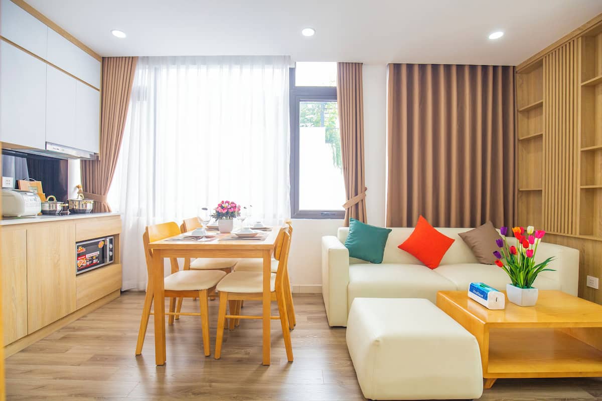A modern living room with a dining area, a sofa, a coffee table, and a kitchen area with a microwave.