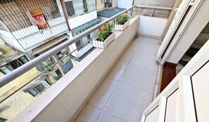 A balcony with a tiled floor, a white railing, and potted plants. - Sumitomo13 Apartment   (Hanoi)