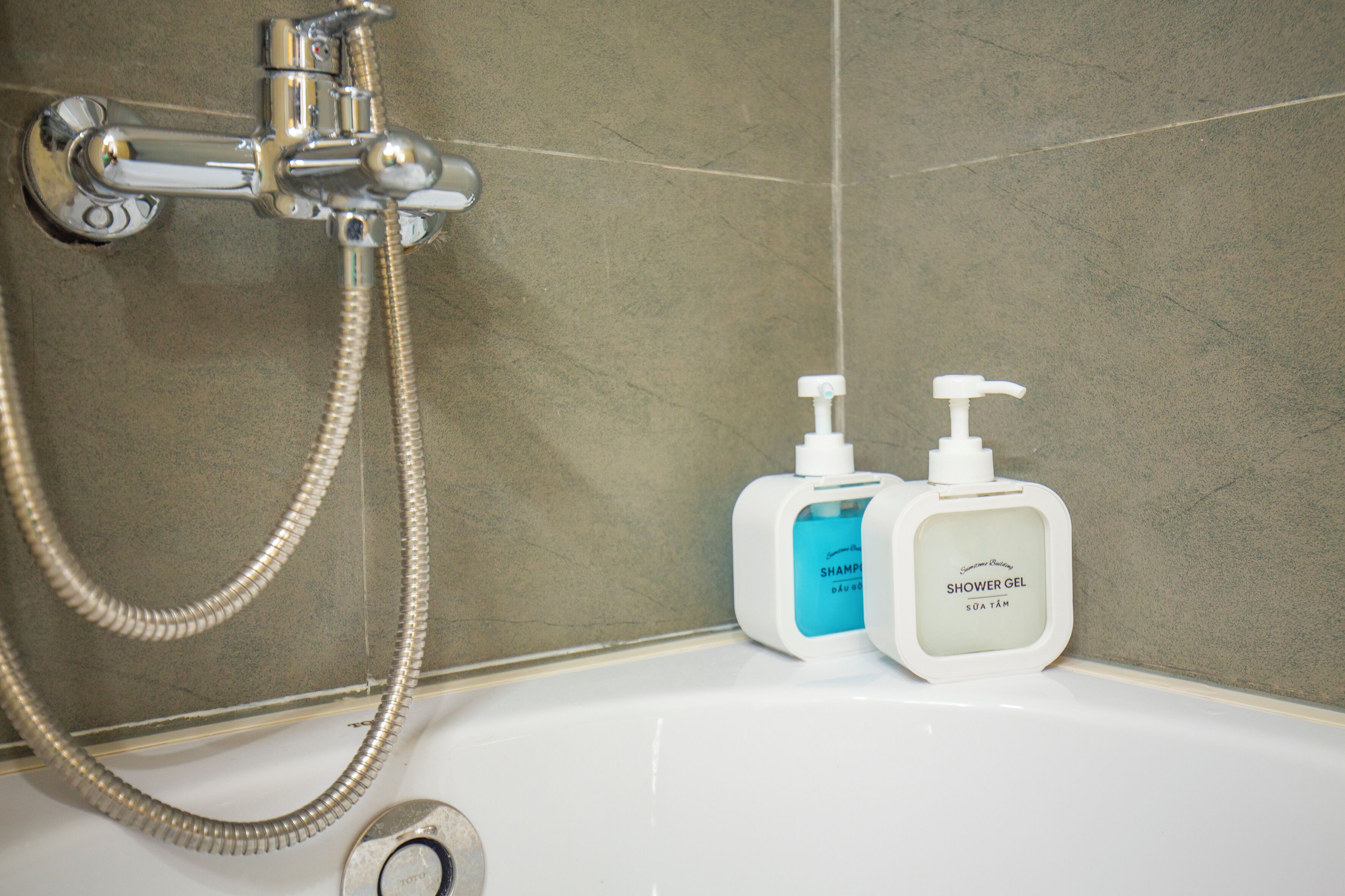Een badkamer met een douche, een handdouche en twee flessen douchegel.