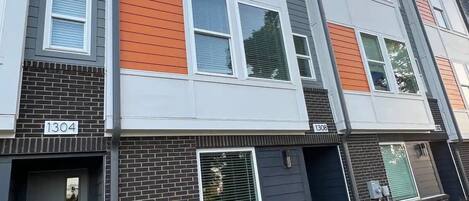 A multi-story residential building with a modern design, featuring a combination of brick and siding exteriors, and numbered units 1304 and 1308.