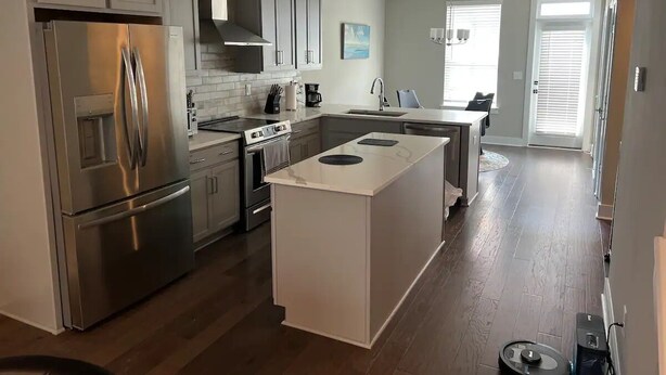 A modern kitchen with stainless steel appliances, a central island, and a dining area with a view.