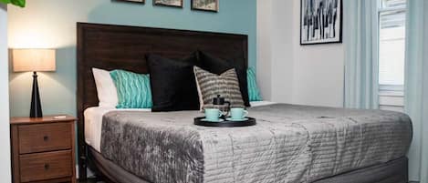 A bedroom with a large bed, a nightstand, a lamp, and artwork on the walls.