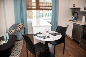 Cocina compacta con comedor, que incluye una mesa redonda, sillas y horno empotrado.