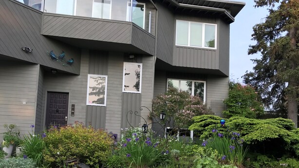 A modern two-story house with a stone retaining wall and a well-maintained garden. - Ravens Run to the Sea - Mere Steps from the Coastal Trail: a multi use bike path (Anchorage)