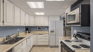 A modern kitchen with white cabinets, stainless steel appliances, and a central island. - Ravens Run to the Sea - Mere Steps from the Coastal Trail: a multi use bike path (Anchorage)