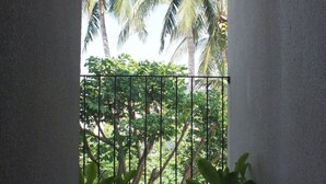 A balcony with a view of palm trees and a metal railing.