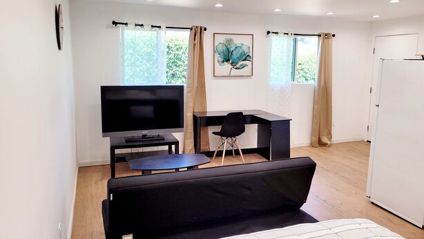 Une chambre moderne équipée d’un téléviseur à écran plat, d’un bureau, d’une chaise et d’un lit.