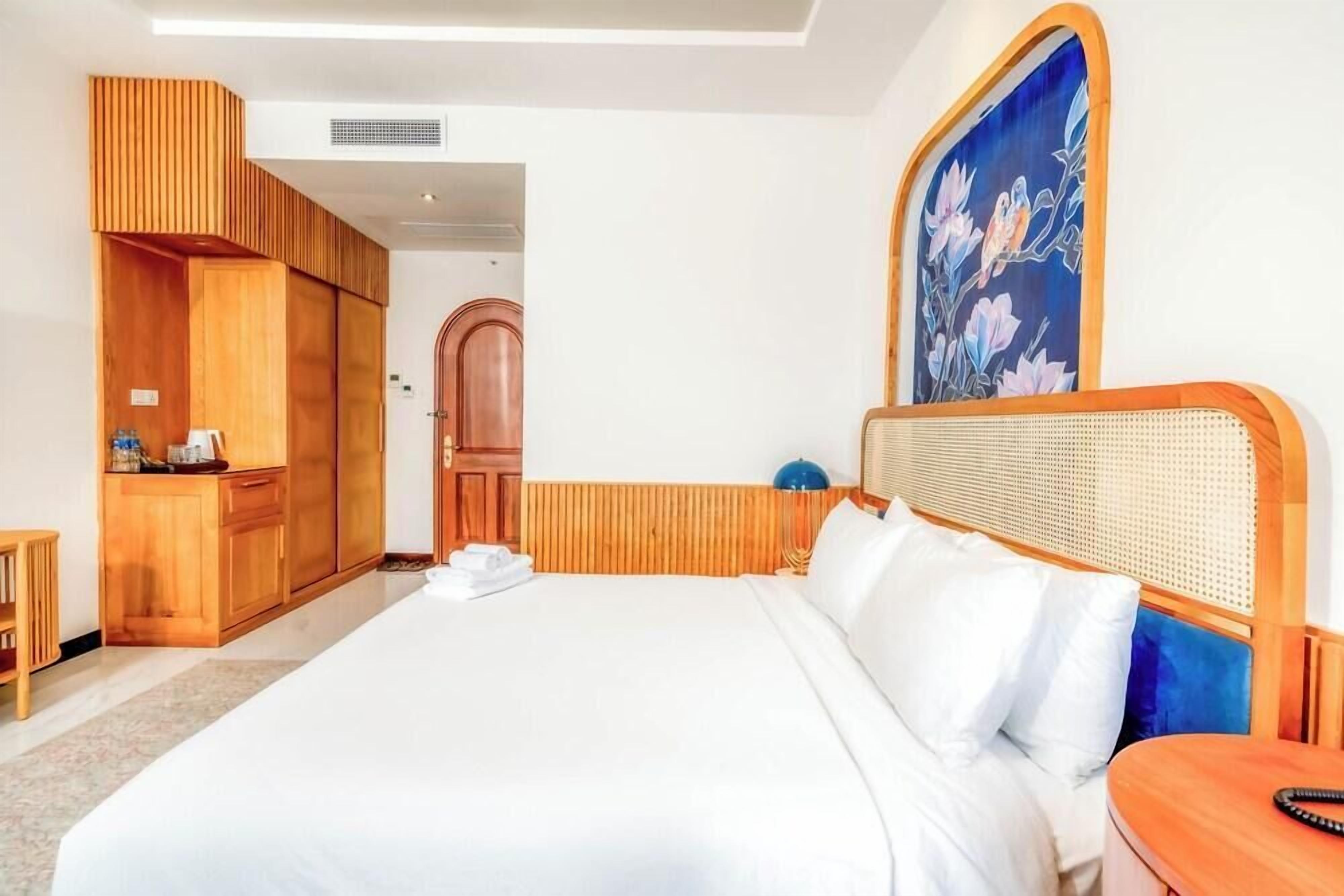 Una camera d'albergo con un letto grande, un'armadio in legno e un quadro appeso al muro.