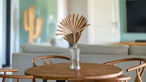 Een ronde houten tafel met een glazen vaas gevuld met een decoratief bloemarrangement.