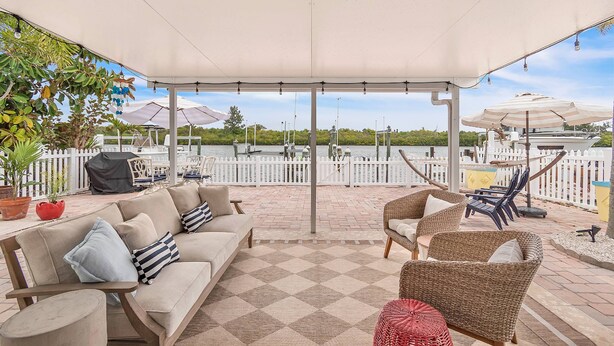 A covered patio with a checkered floor, outdoor furniture, and a view of the water.