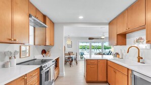 A modern kitchen with wooden cabinets, a stainless steel range, and a large window overlooking a deck.