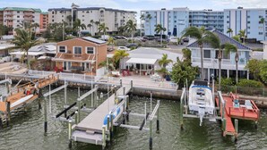 A marina with docked boats, a wooden pier, and a building with a balcony overlooking the water.