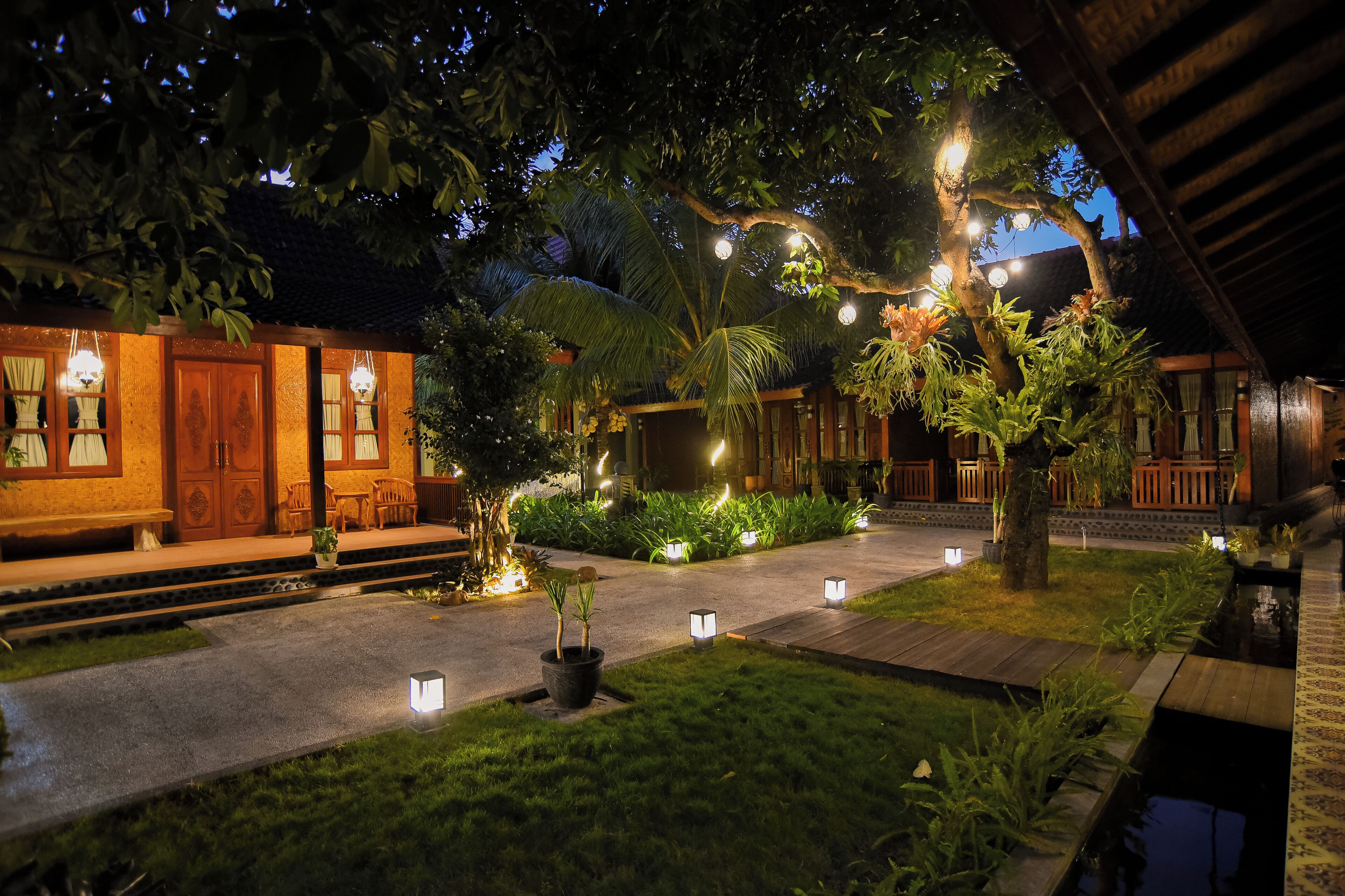 A well-lit courtyard with a wooden fence, potted plants, and a small water feature.