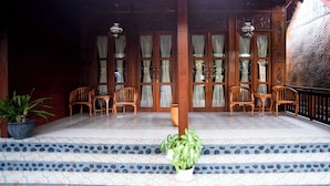 A traditional wooden entrance with a tiled floor, potted plants, and wooden chairs. - Ndalem Mataram (Banyuwangi)