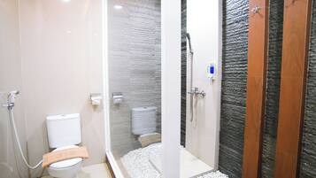 Un baño moderno con inodoro, ducha y mampara de vidrio.