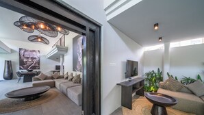 A modern living room with a sectional sofa, a round coffee table, and a TV stand.