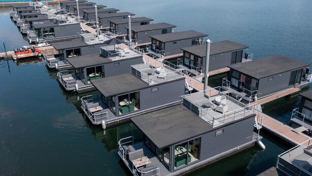 Een jachthaven met drijvende woningen, voorzien van balkons, terras en directe toegang tot het water.