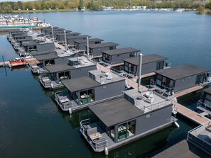 A marina with floating homes featuring balconies, outdoor seating, and direct water access.