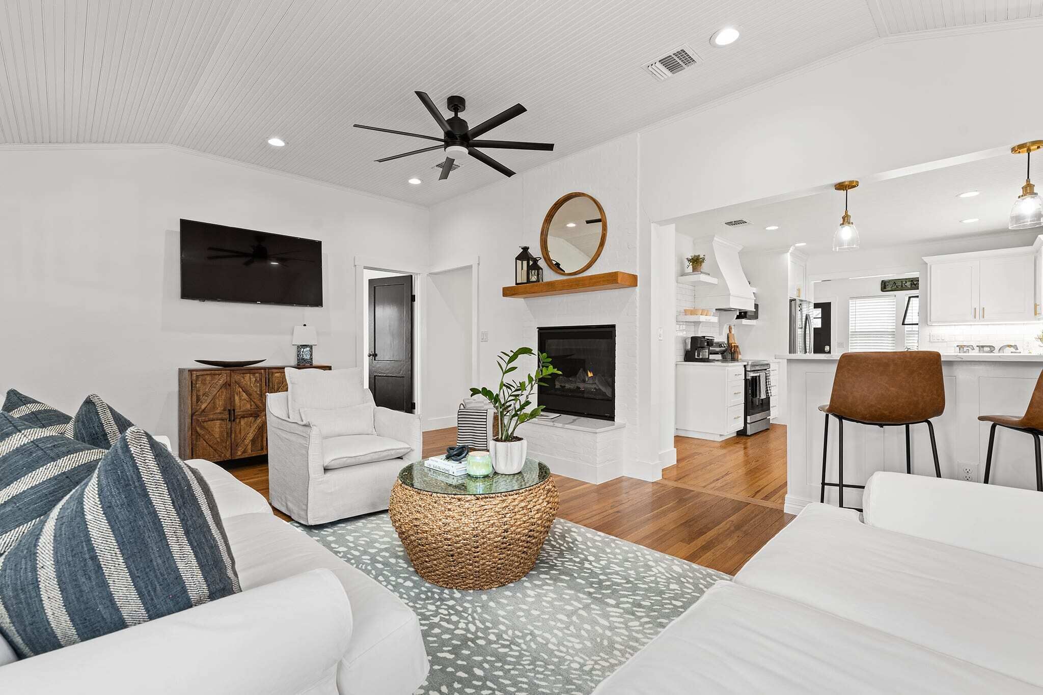 A modern living room with a fireplace, a dining area, and a kitchen.