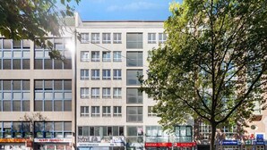 A multi-story building with commercial spaces on the ground floor, including a pharmacy and a pub. - Munich Gem - 2 Bedroom Alpine View Tranquility (München)