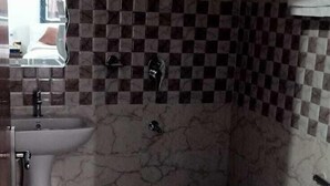 A bathroom with a sink, mirror, and a checkered wall pattern. - BRAJDHAM HOTEL BARSANA (Chhata)