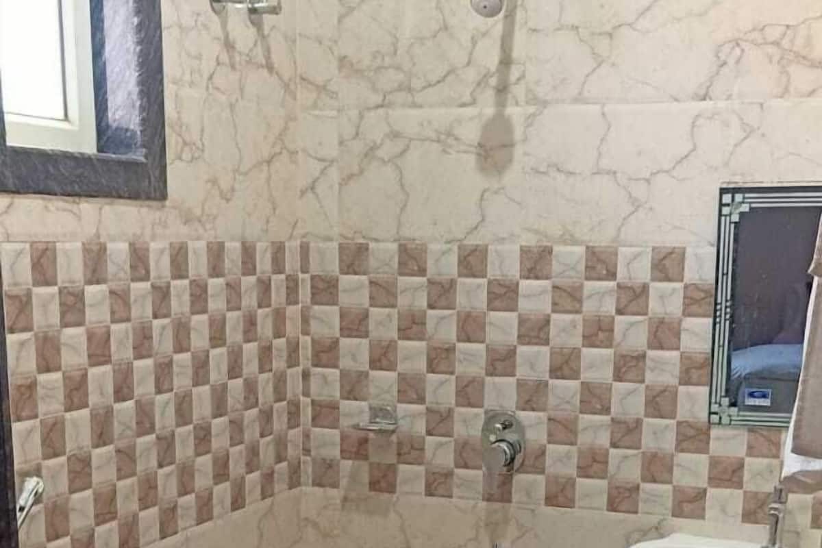 Un baño con inodoro, lavamanos, ducha y un cesto de ropa azul.