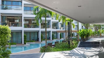 Un hotel moderno con piscina, zona de estar al aire libre y abundante vegetación.