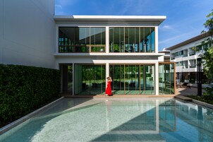 A modern building with large glass windows and a pool area.