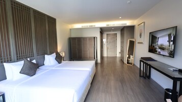 A hotel room with a large bed, a desk, a mirror, and a wardrobe.