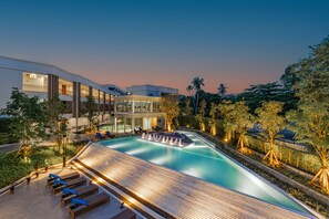Un hotel moderno con piscina, zonas de descanso y jardín ajardinado.