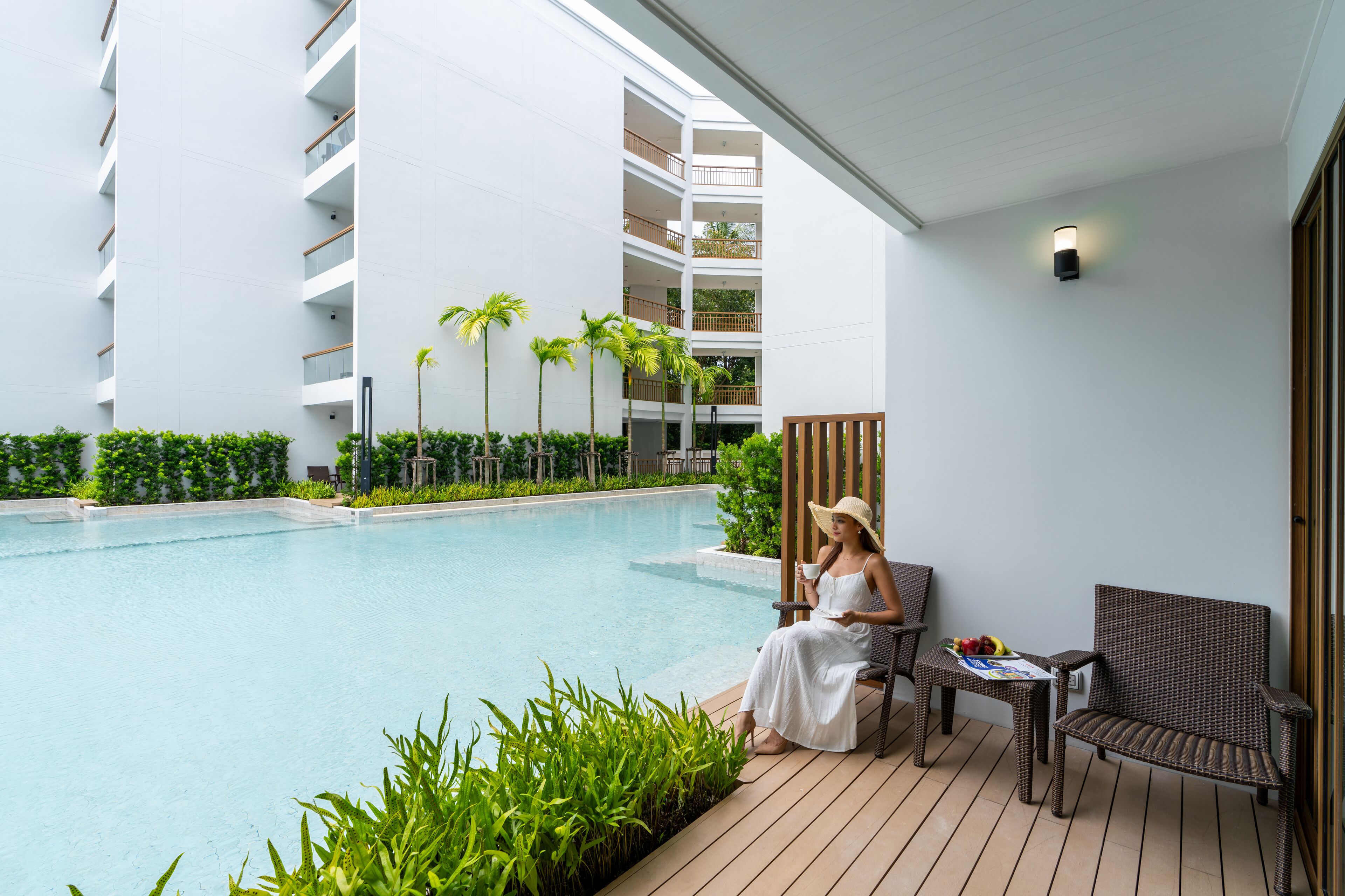 A poolside area with a seating arrangement, a pool, and a building with multiple balconies.