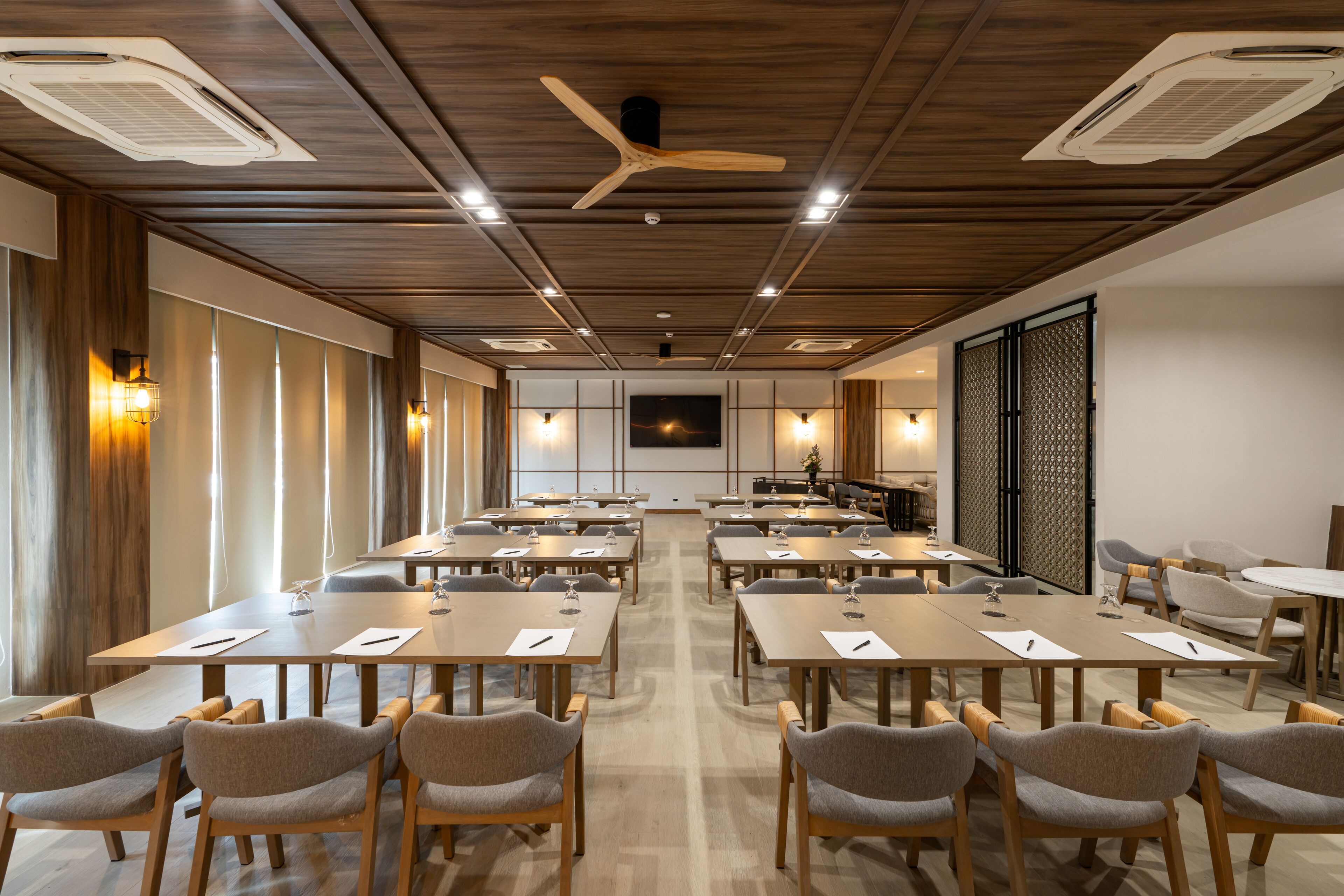 A conference room with multiple tables and chairs, wooden ceiling, and ceiling fans.