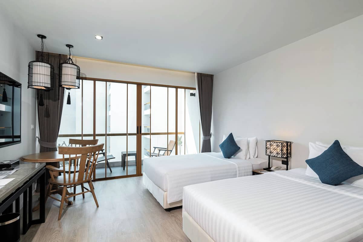 A hotel room with two beds, a desk, and a dining area.